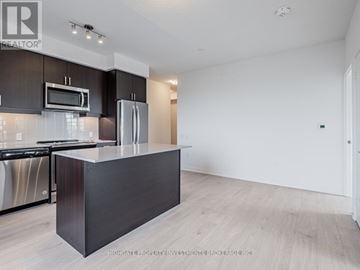 Mississauga (Hurontario) condo for rent - A modern kitchen with a stainless steel refrigerator and microwave above a central island.