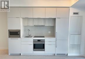 Toronto (Oakwood Village) condo for rent - A white kitchen with a sink, stove, and refrigerator.