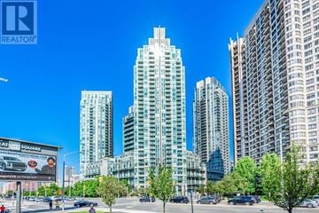 Mississauga (City Centre) condo for rent - A cityscape with tall buildings and a billboard for a realtor.