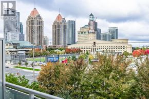 Mississauga (City Centre) condo for rent - A cityscape with a mix of modern and older buildings, trees with autumn foliage, and a cloudy sky.