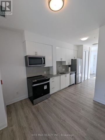 Toronto (Scarborough Village) condo for rent - A kitchen with white cabinets and a microwave above the stove.