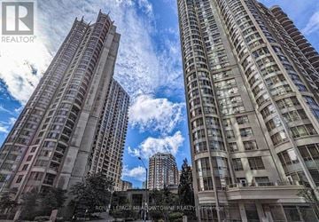 Mississauga (City Centre) condo for rent - Two tall buildings are seen from the ground up, with a clear blue sky above.