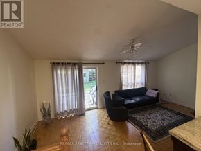 Mississauga (Central Erin Mills) apartment for rent - A living room with a black couch and a ceiling fan.