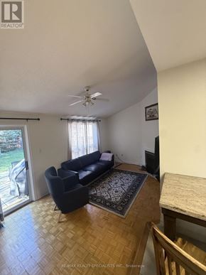 Mississauga (Central Erin Mills) apartment for rent - A living room with a black couch and a ceiling fan.