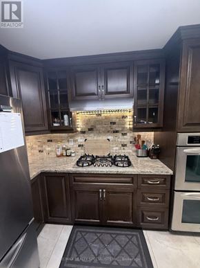 Mississauga (Central Erin Mills) apartment for rent - A kitchen with dark wood cabinets and a granite countertop.