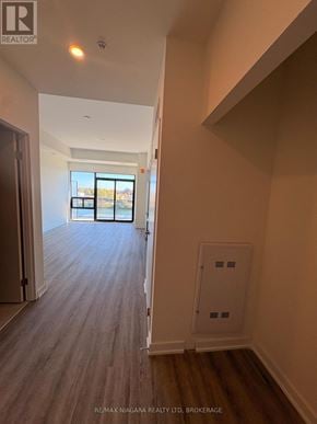 Welland (Broadway) condo for rent - A hallway with wooden floors and a door leading to a balcony.