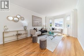 Brampton (Sandringham-Wellington) apartment for rent - A living room with a white couch, a coffee table, and a large painting on the wall.