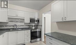 St. Catharines (Vine/Linwell) townhouse for rent - A kitchen with white cabinets and a granite countertop.