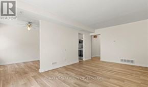 St. Catharines (Vine/Linwell) townhouse for rent - A spacious room with wooden flooring and white walls, with a ceiling fan and a doorway leading to another room.