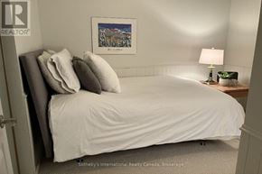Collingwood townhouse for rent - A bedroom with a bed, pillows, a lamp, and a framed picture on the wall.