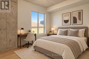 Hamilton (Westdale) condo for rent - A bedroom with a large bed, a desk with a chair, and two framed pictures on the wall.