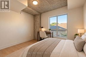 Hamilton (Westdale) condo for rent - A bedroom with a large bed and a view of the outdoors through a window.