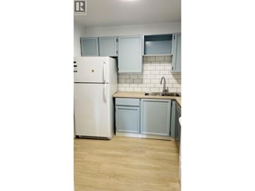 Richmond apartment for rent - A white refrigerator is in a kitchen with light wood floors and white cabinets.
