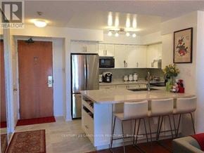 Toronto (Willowdale East) condo for rent - A kitchen with a refrigerator, sink, and bar stools.