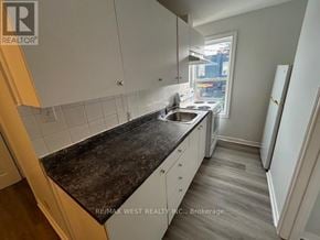 Toronto (Weston-Pellam Park) apartment for rent - A kitchen with white cabinets and a black countertop.