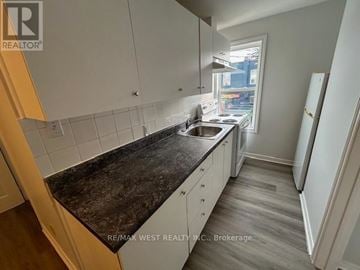 Toronto (Weston-Pellam Park) apartment for rent - A kitchen with white cabinets and a black countertop.