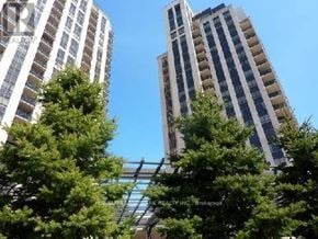Toronto (Banbury-Don Mills) condo for rent - Two tall buildings are seen behind some trees.