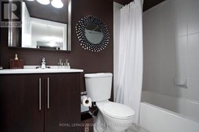 Toronto (Willowdale East) condo for rent - A white toilet sits in a bathroom with brown cabinetry and a white shower curtain.