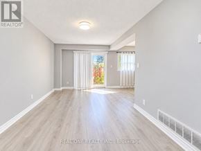 Toronto (L'amoreaux) townhouse for rent - A spacious room with light wood flooring and white walls, with a sliding glass door leading to a garden.