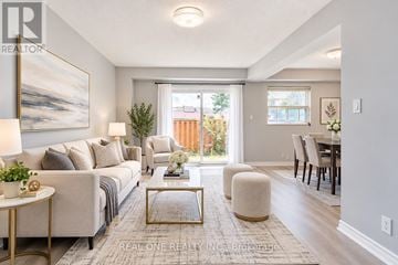 Toronto (L'amoreaux) townhouse for rent - A well-lit living room with a large painting on the wall and a dining area in the background.