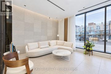 Pickering (Bay Ridges) condo for rent - A living room with a white couch and a wooden chair.
