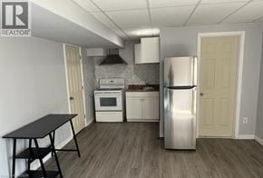 Niagara Falls apartment for rent - A kitchen with a stainless steel refrigerator, a black table, and white cabinets.