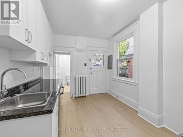 Toronto (Corso Italia-Davenport) triplex for rent - A kitchen with white cabinets and a black countertop.