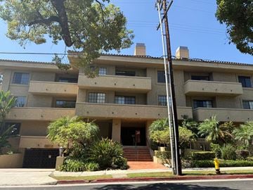 Pasadena apartment for rent - A building with a brown roof and tan walls with a tree in front of it.