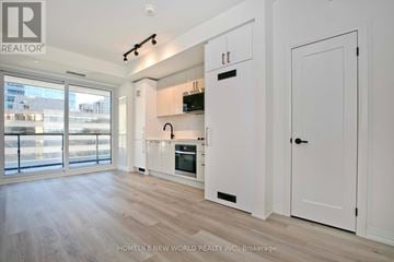 Toronto (Kensington-Chinatown) condo for rent - A modern kitchen with white cabinets and a wooden floor.