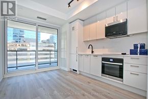 Toronto (Kensington-Chinatown) condo for rent - A modern kitchen with white cabinets and a wooden floor.