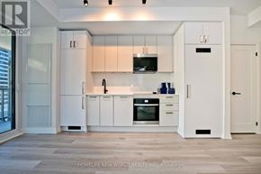 Toronto (Kensington-Chinatown) condo for rent - A modern kitchen with white cabinets and appliances.