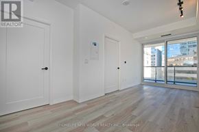 Toronto (Kensington-Chinatown) condo for rent - A room with white walls and wooden flooring, with a door on the left and a balcony on the right.