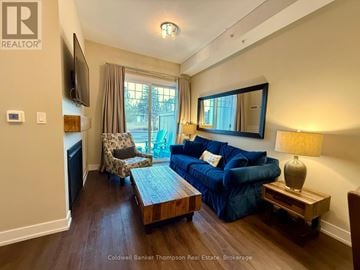 Huntsville (Chaffey) condo for rent - A living room with a blue couch and a wooden coffee table.