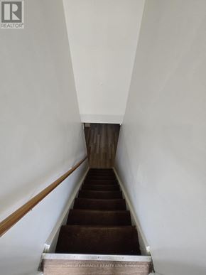 Toronto (L'amoreaux) apartment for rent - A staircase with a wooden handrail and brown carpeted steps.