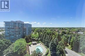 Brampton (Queen Street Corridor) condo for rent - A tall building with a swimming pool in the foreground and a row of trees in the background.