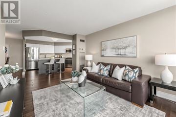 Brampton (Queen Street Corridor) condo for rent - A modern living room with a glass coffee table and a brown leather couch.
