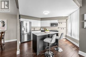 Brampton (Queen Street Corridor) condo for rent - A modern kitchen with a bar stool and a refrigerator.