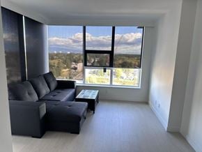 Surrey apartment for rent - A black leather sofa sits in a white room with a view of the city.