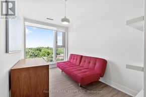 Ottawa condo for rent - A red sofa in a white room with a view of trees outside the window.