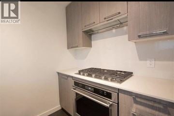 Richmond townhouse for rent - A modern kitchen with a stove top oven and a microwave above it.