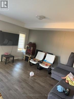 Thorold (Rolling Meadows) apartment for rent - A living room with a grey couch, a white chair, and a TV mounted on the wall.