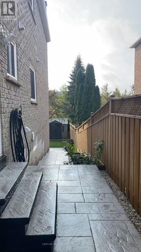 Markham (Markville) apartment for rent - A wet stone walkway leads from a house to a wooden fence.