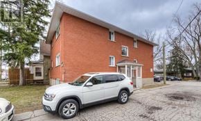 Kitchener multi-family for rent - A red brick house with a white SUV parked in front.