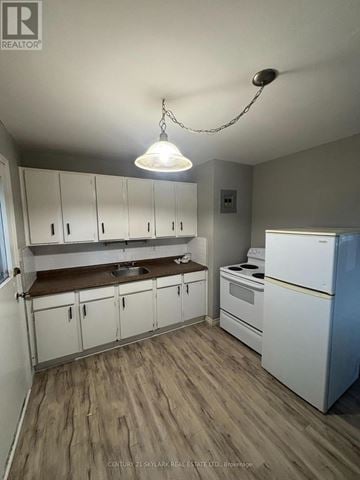 Kitchener multi-family for rent - A kitchen with white cabinets and a white fridge.