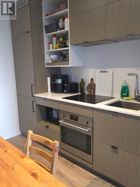 Toronto (Bay Street Corridor) condo for rent - A kitchen with wooden cabinets and a wooden chair.