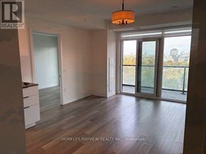 Toronto (Moss Park) condo for rent - A room with a wooden floor and a large window with a view of the city.