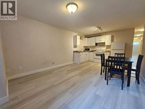 Burnaby apartment for rent - A kitchen with a table and chairs in the foreground and a microwave, oven, and cabinets in the background.