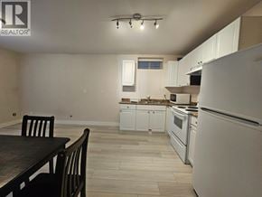 Burnaby apartment for rent - A kitchen with white appliances and a dining table.