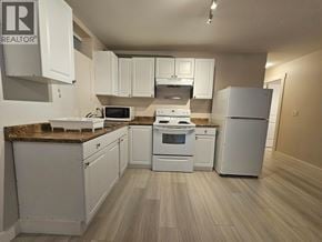 Burnaby apartment for rent - A kitchen with white appliances and cabinets.