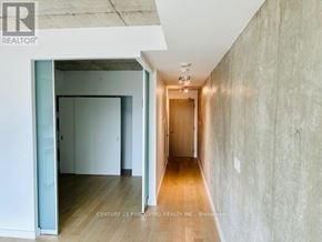 Toronto (Waterfront Communities) condo for rent - A hallway with a wooden floor and concrete walls.